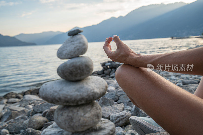 日落时分在湖边的stack rock附近练习瑜伽和冥想的人的细节